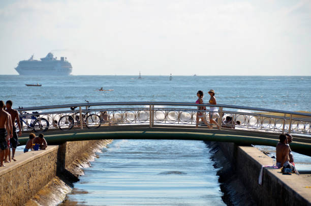 ciudad de santos, brasil. chicas cruzando el puente sobre el canal de agua. gente disfrutando del día soleado en la playa. crucero saliendo de la ciudad. - horizon over water environment vacations nature fotografías e imágenes de stock