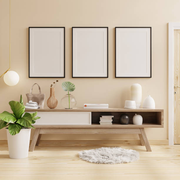 크림 벽 배경에 식물과 밝은 방에 캐비닛에 검은 프레임 포스터. - designer living room brown white 뉴스 사진 이미지