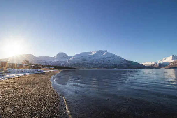 Breathtaking wildlife of the northernmost part of Norway, Finnmark in the small village of Skibotn. The snow-capped hills of the Lyngen alps along with the sea and the sunset. Scandinavian landscape.