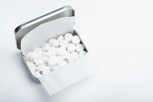 Mint candies on a white background. White mint candies in an open tin box. Fresh breath or bad breath concept.