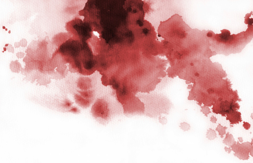 Red ink stain with drips and splashes on a textured paper.