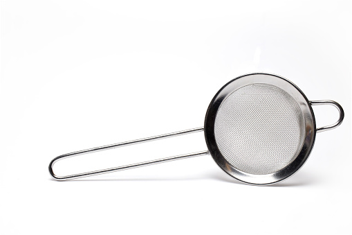 Close up of small silver metal strainer tea kitchen strainer on white background