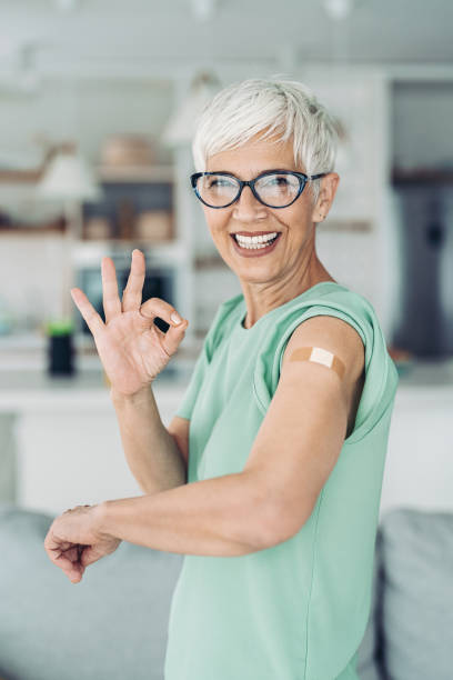 Just got her booster dose Smiling senior woman showing her arm after a vaccination one senior woman only stock pictures, royalty-free photos & images