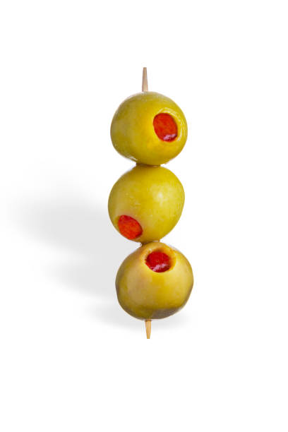 Three green olives with red pepper on a toothpick isolated on white background