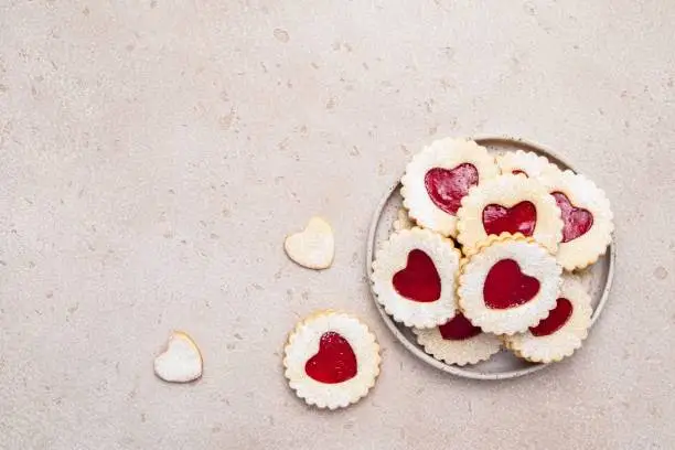 Linzer cookies in shape of heart with jam on light background. Mother's day, Women's day, Valentine's day. Homemade present. Copy space, top view.