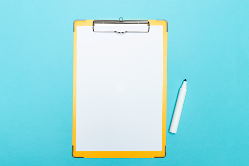 Yellow clipboard with blank paper and red marker on blue background.