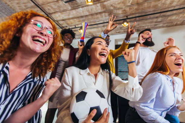 Happy casual business people or football fans watching soccer on tv and celebrating victory. Friendship, sports and entertainment concept. stock photo