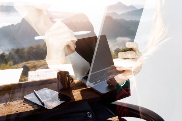 Computer Monitor, Keyboard, coffee cup and Mouse with Blank is on the work table at the sky mountain river and trees front view background.