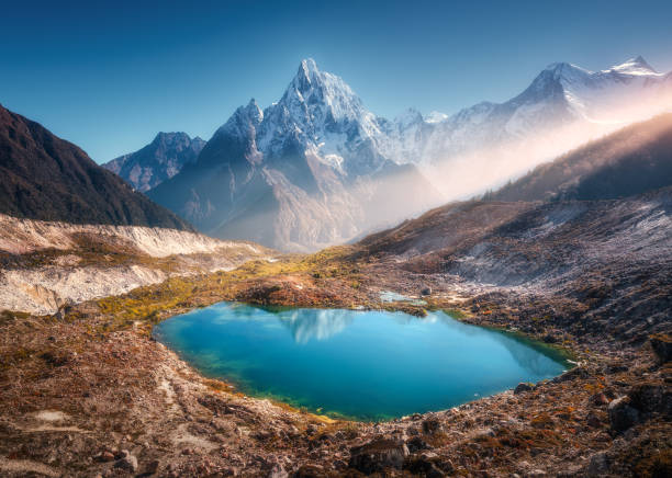 istock Snowy mountain with illuminated peaks and small lake at sunrise 1362960301