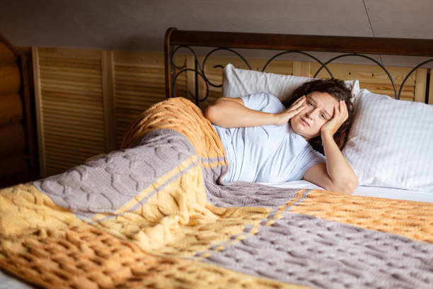 istock Sad curly brunette woman lying on bed under terry covers with worried face having inner problems wearing home pajamas in daytime. Anxiety moment in adult life 1362960443
