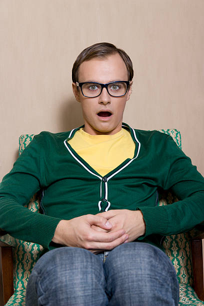 shocked young cute guy sitting on the chair stock photo