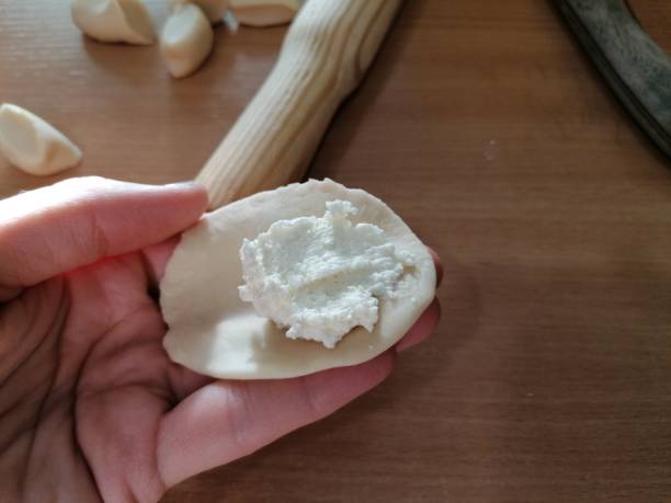 istock A hand holding a small rolled cake of dough with cottage cheese for dumpling. 1362969068