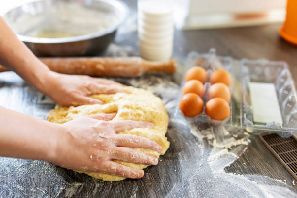 mãos femininas fazendo massa para assar em mesa de madeira perto de rolo, ovos e garrafa de leite. culinário, cozinha, conceito de cozimento - baking cake making women - fotografias e filmes do acervo