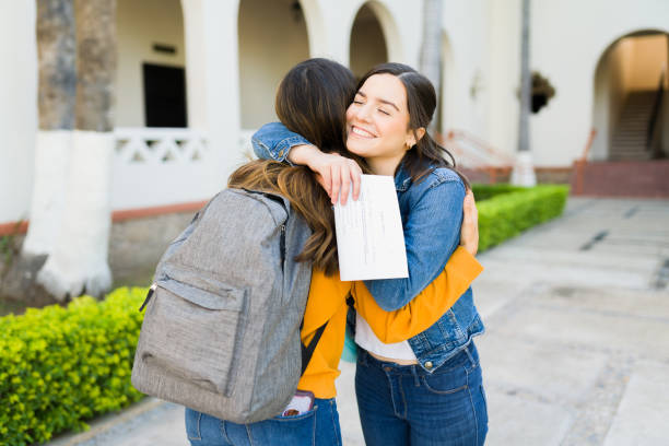 Passing her exams with good grades I got into college! Cheerful young woman hugging her best friend after getting her acceptance letter college acceptance letter stock pictures, royalty-free photos & images