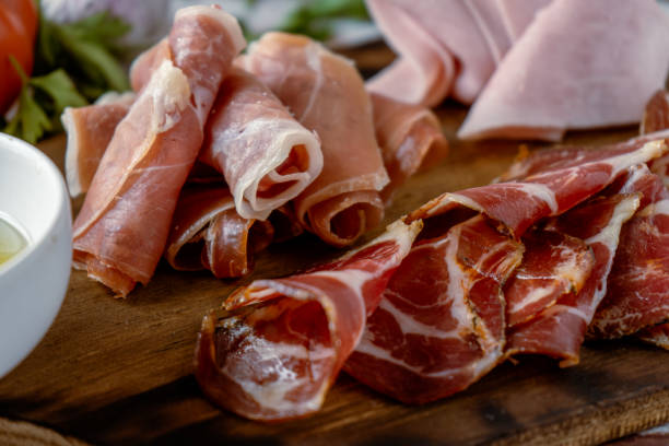 widok z bliska na pyszny stół z szynką serrano, gotowaną szynką i marynowanym tyłkiem wieprzowym w towarzystwie czarnych oliwek. koncepcja przystawki, - delicatessen meat cold cuts chopped zdjęcia i obrazy z banku zdjęć