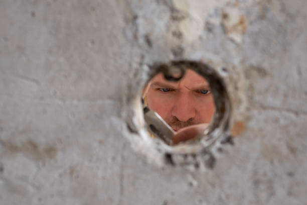 istock View on hole in wall where handyman is repairing wires cutting them. 1362976181