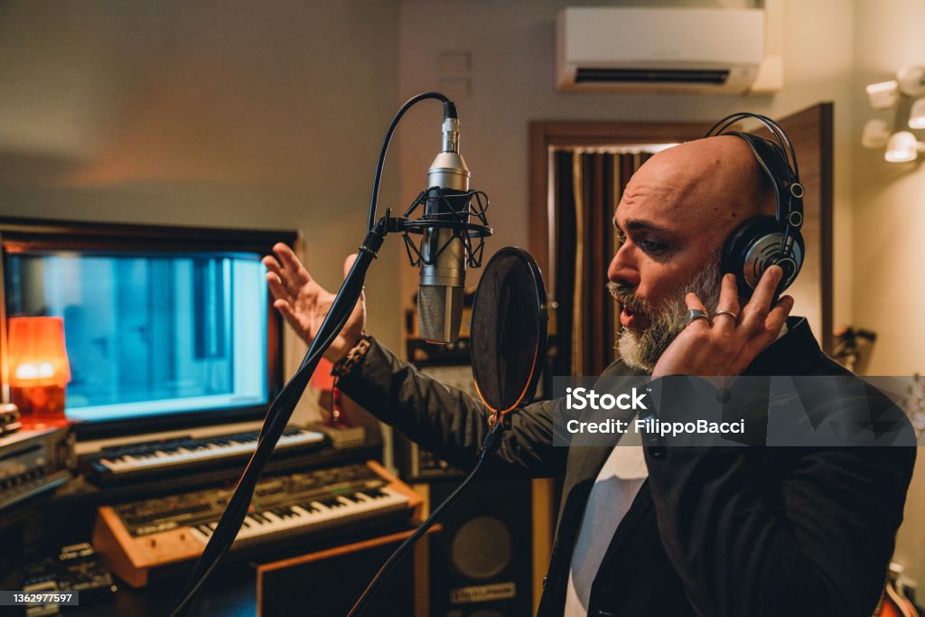Singer is recording music in a professional recording studio Singer is recording music in a professional recording studio. He's singing nad he's making gestures with hands. 35-39 Years Stock Photo