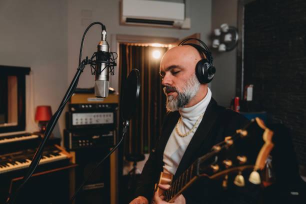 istock Musician plays guitar and sings in a recording studio 1362977614