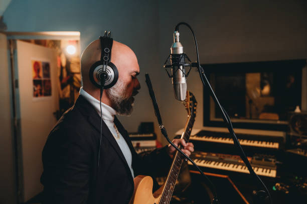 istock Musician plays guitar and sings in a recording studio 1362977636