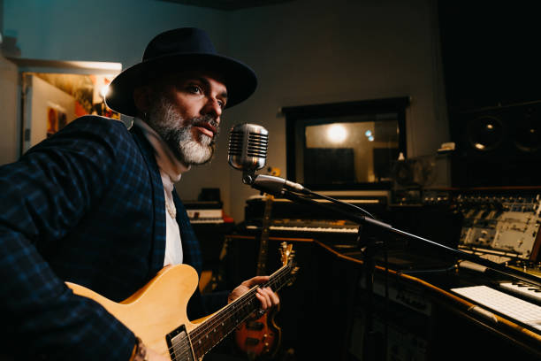 istock A musician is playing guitar and singing in a professional recording studio 1362977653