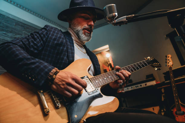 istock A musician is playing guitar and singing in a professional recording studio 1362977663