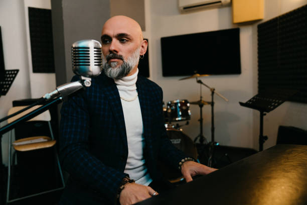 A musician is playing piano in a professional recording studio. He's playing and singing.