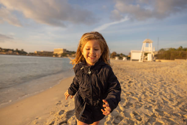 istock Cute smiling little girl running on beach on sunset 1362977886