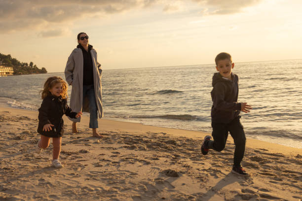 Mother spending time with her two kids on beach stock photo
