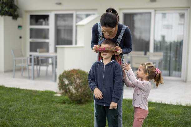 istock Young mother and two kids playing hide and seek in back yard 1362978794