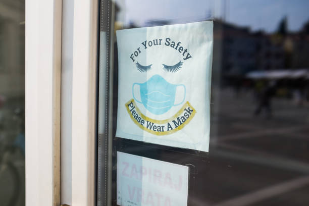 Window sing informing people to wear a protective face mask indoors