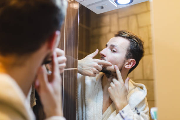 jeune homme en peignoir faisant éclater des boutons tout en se regardant dans le miroir après une douche - toothbrush brushing teeth brushing dental hygiene photos et images de collection