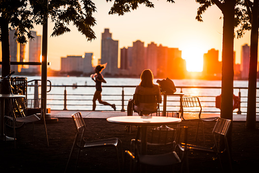 Woman watching pedestrians a Break in New York's Hudson River at Sunset
