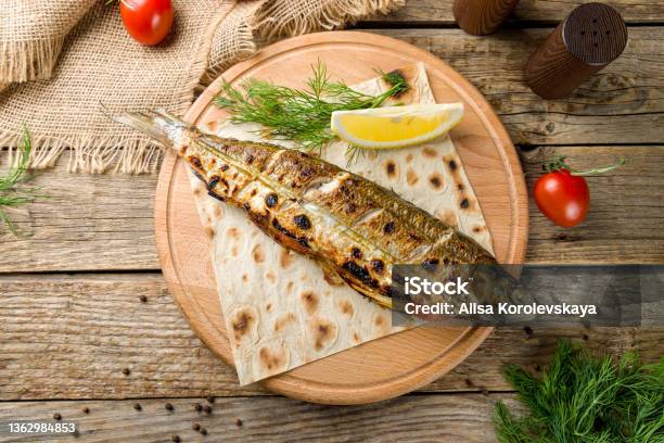 Fried Sea Bass On The Board With Lemon Top View On Old Wooden Table Stock Photo - Download Image Now