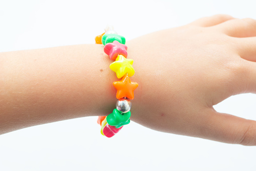 colorful bracelet on arm of little girl on isolated white background