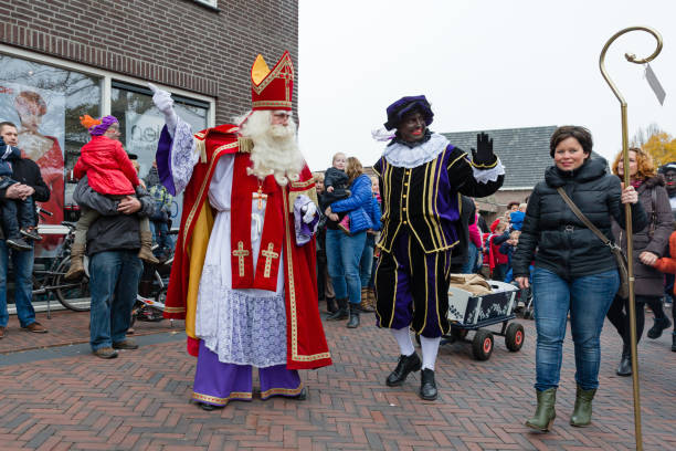 Arrival parade of 'Sinterklaas' and his 'zwarte pieten' in Wierden Wierden, Twente, Overijssel, Netherlands, november 16th 2013, parade of Sinterklaas and his 'zwarte pieten' with blackface in the streets of Wierden at the annual arrival of Sinterklaas (Saint Nicholas), a large group of people have come to watch and join the parade - traditionally the arrival of Sinterklaas, from Spain, takes place mid november, while the gift-giving day is on december 5th zwarte piet stock pictures, royalty-free photos & images