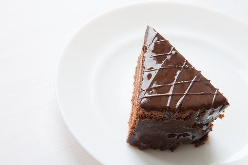 A piece of chocolate cake is on a white plate. Close-up cake.