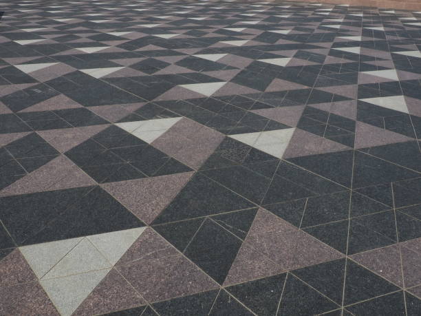 istock The square is paved with triangular tiles. Grey, white, black tiles on the street. The cobblestone surface. Modern design of streets, avenues, squares, shopping centers. Wear-resistant flooring. 1362991473