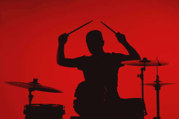 istock Silhouette of a young man playing drums on a red background 1362993327
