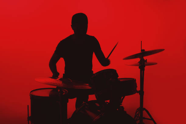 istock Silhouette of a young man playing drums on a red background 1362993335