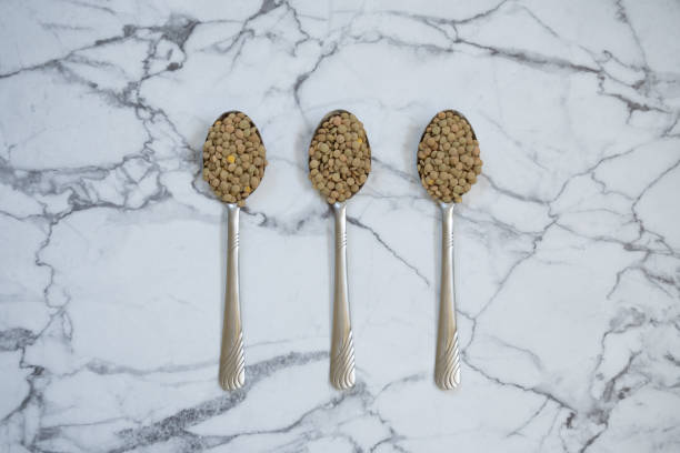 Three spoons with lentils Three spoons with lentils on marble table with copy space vitamin b 3 stock pictures, royalty-free photos & images