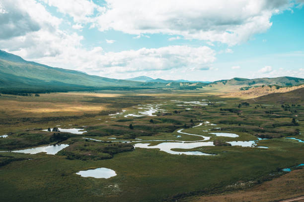 istock Surreal mountain scenery with lake system on tableland among forest hills. Scenic landscape with lakes group on plateau. Lakes system and channels in wide valley. System of lakes in surrealist colors. 1363005803