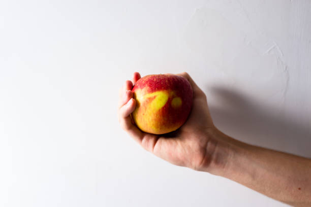 istock A hand holding an apple against white background. 1363005865