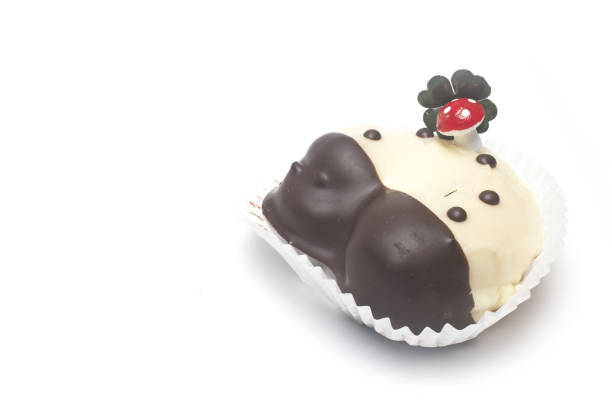 Close up of sweet dessert in the shape of horseshoe with lucky mushroom and four leaf clover on it as lucky charm for New Year on white background