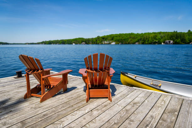Two Adirondack chairs and a yellow canoe stock photo