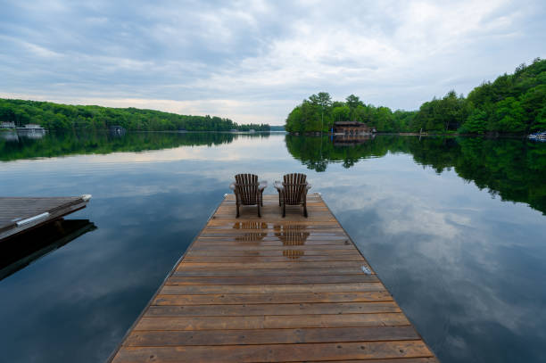 istock Adirondack chairs on a wet wooden dock facing a lake 1363024123