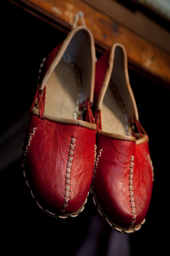 A pair of traditional hand made red Turkish shoes, called Yemeni, hang from the ceiling