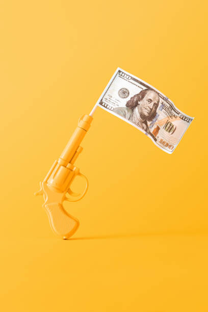 Money flying from a fired pistol on yellow background. Monochrome still life