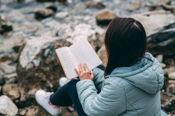 istock Young Woman Reading a Book on the Beach 1363036340