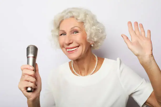 Photo of Portrait of charming modern grandmother holds up the microphone