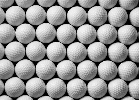 White golf ball on green background. Horizontal composition.